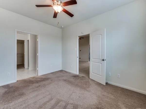 a view of an empty room and chandelier fan