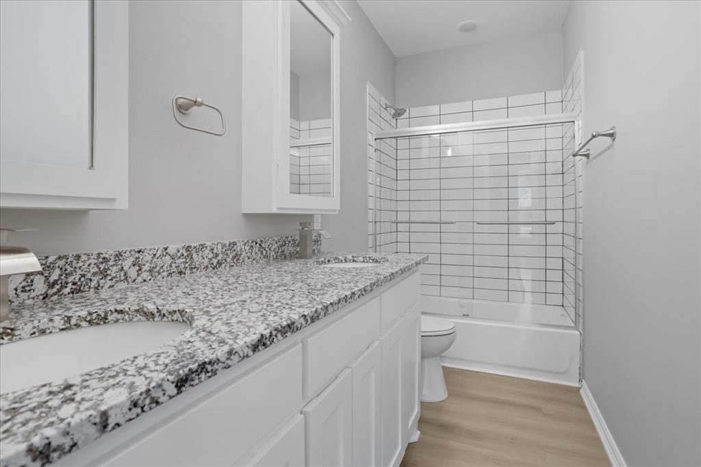 215 East Nelson Street Denison, TX 75021 - Photo 20 of 27 a bathroom with a granite countertop sink a toilet and shower