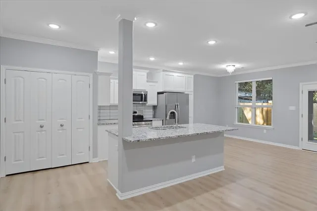 a large kitchen with granite countertop a large counter top a sink stainless steel appliances and cabinets