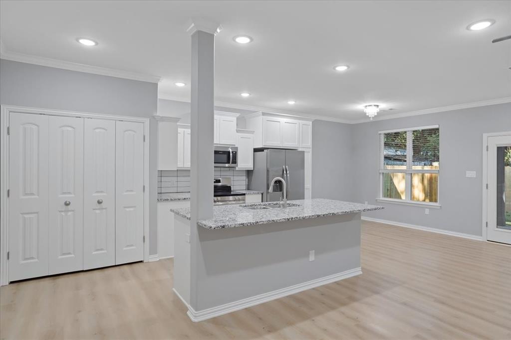 215 East Nelson Street Denison, TX 75021 - Photo 3 of 27 a large kitchen with granite countertop a large counter top a sink stainless steel appliances and cabinets