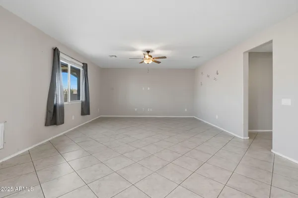 an empty room with ceiling fan and windows