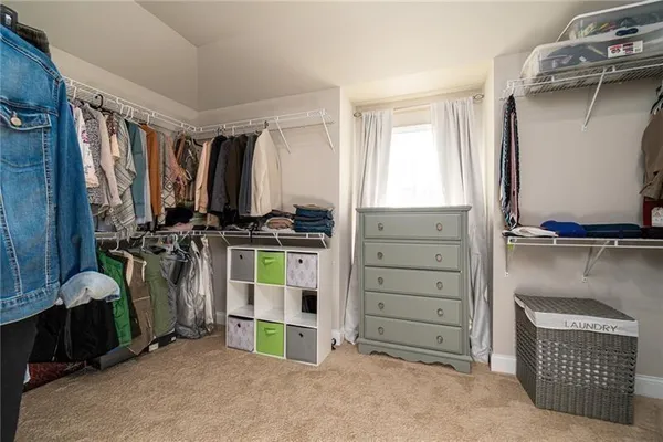 a view of walk in closet with clothes and shoes