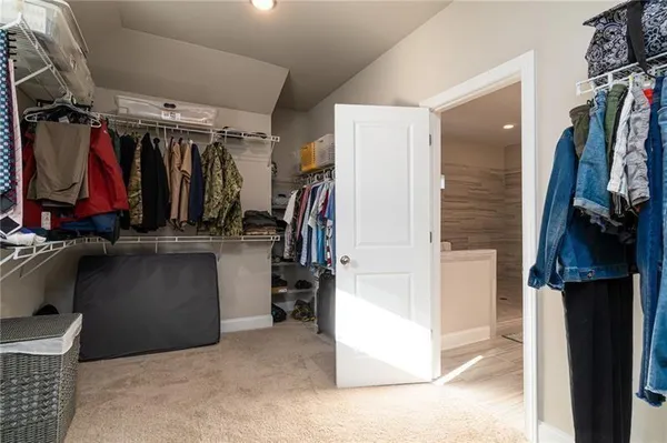 a view of walk in closet with clothes and shoes