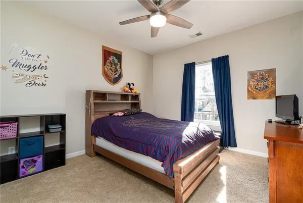 a bedroom with a bed and a flat tv screen on dresser