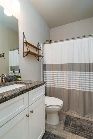 a bathroom with a granite countertop sink a toilet and a mirror