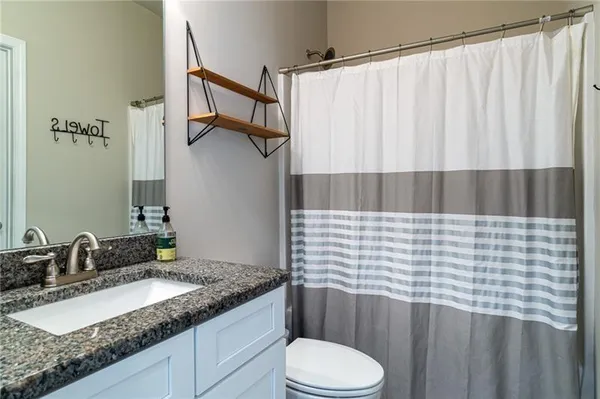 a bathroom with a granite countertop sink toilet and shower