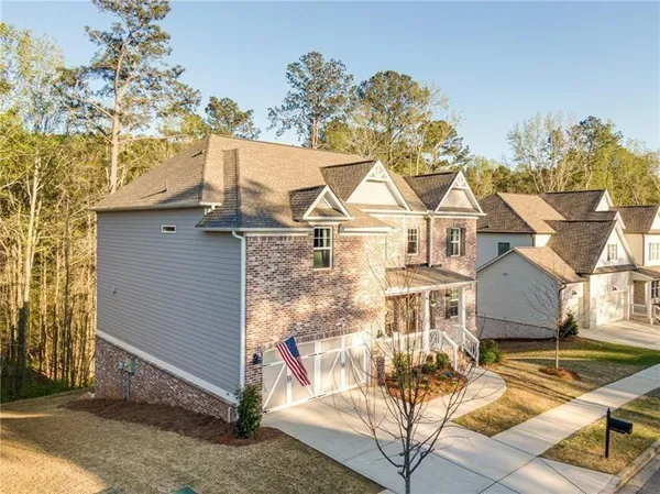 a view of a white house with a large tree and table and chairs