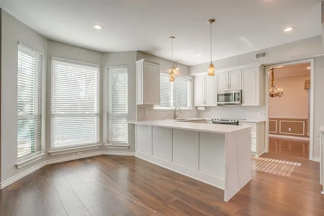 a large kitchen with granite countertop a large window and white cabinets