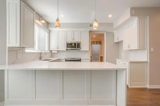 a kitchen with kitchen island granite countertop a sink cabinets and wooden floor