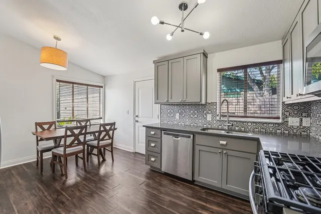 a kitchen with stainless steel appliances granite countertop a dining table chairs stove and white cabinets