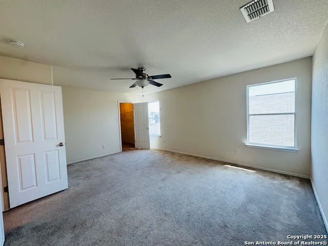 an empty room with windows and fan