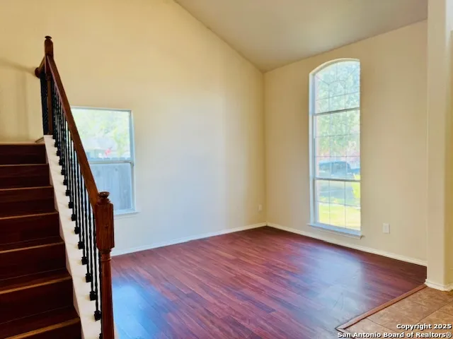 a view of an empty room with wooden floor and stairs