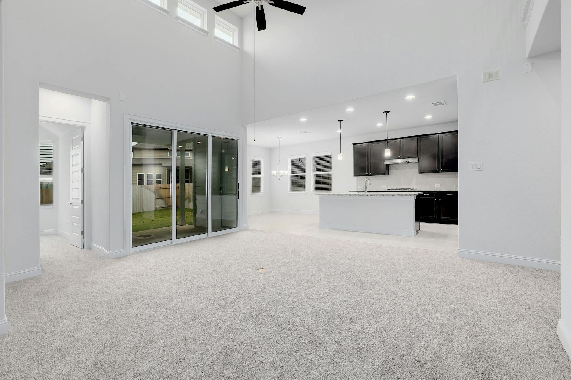 2040 Base Burner Path Leander, TX 78641 - Photo 2 of 31 Unfurnished living room featuring light carpet, ceiling fan, a high ceiling, and a chandelier