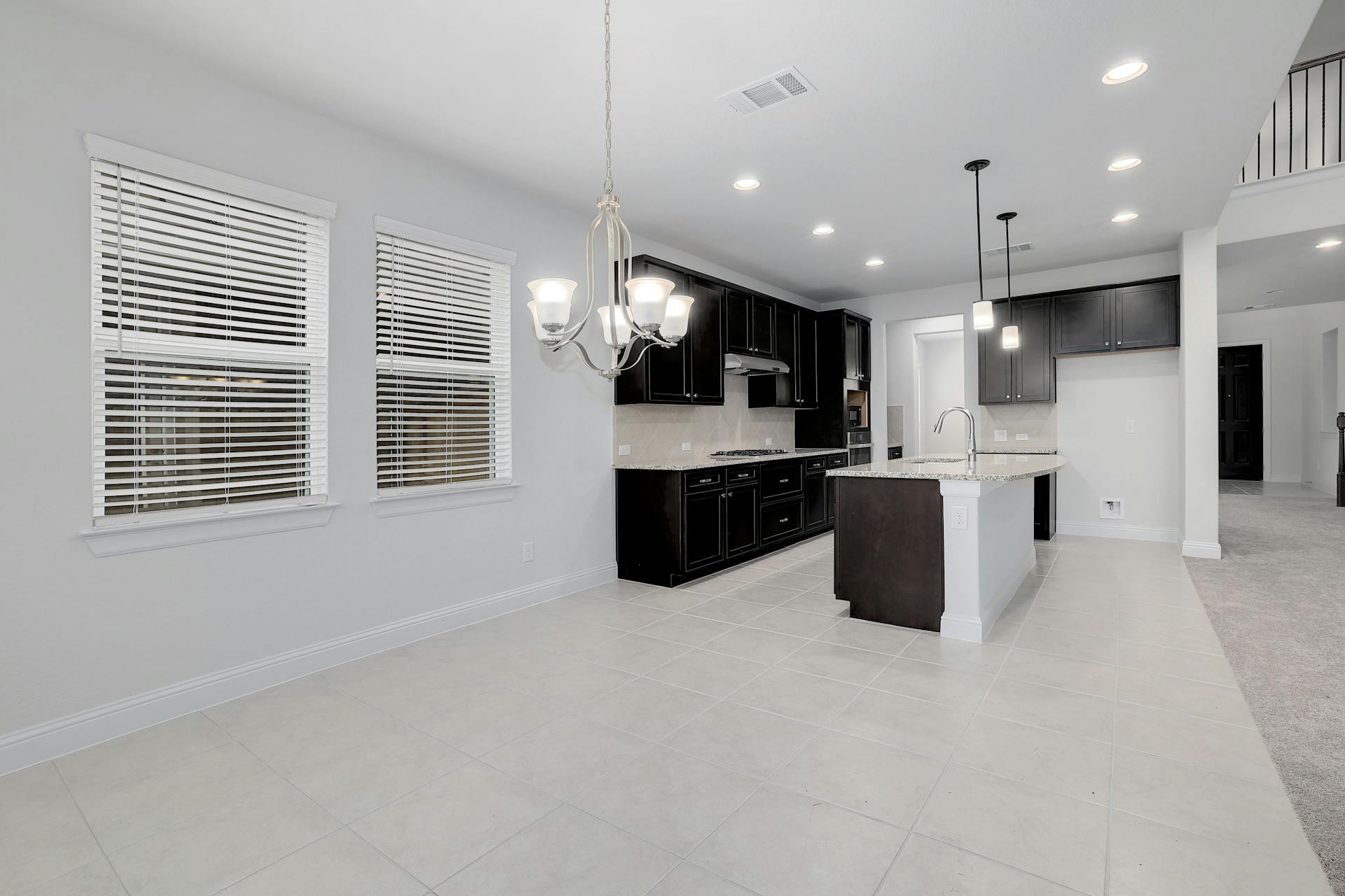 2040 Base Burner Path Leander, TX 78641 - Photo 6 of 31 Kitchen featuring light tile patterned floors, a kitchen island with sink, dark cabinets, light stone countertops, and suspended lighting