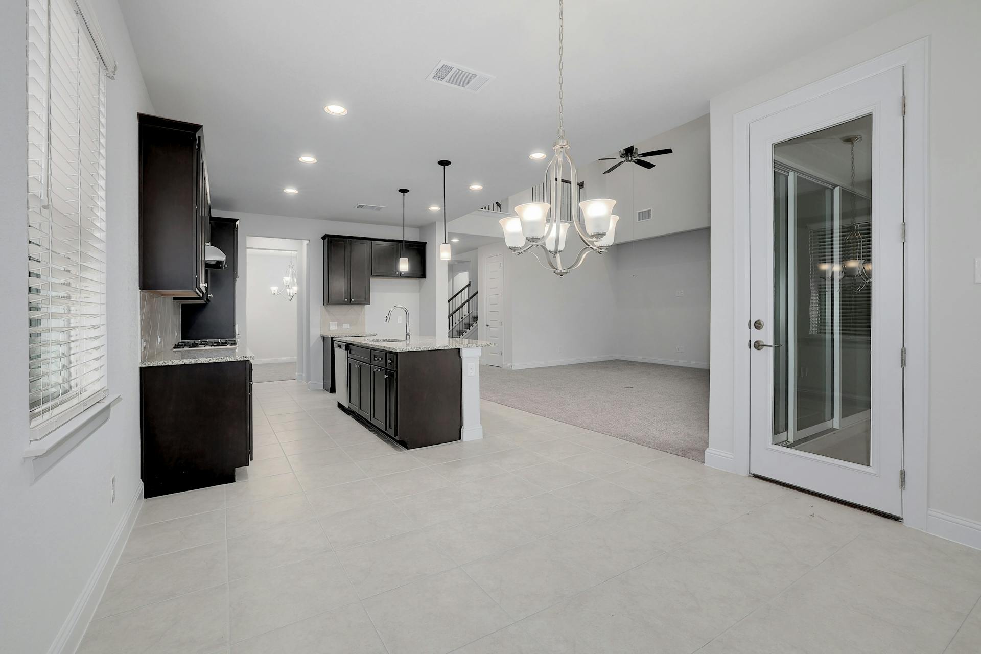 2040 Base Burner Path Leander, TX 78641 - Photo 31 of 31 Kitchen with a chandelier, a kitchen island with sink, light stone counters, open floor plan, and light tile patterned floors