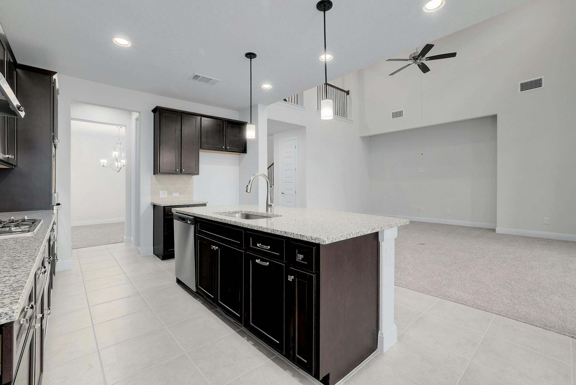 2040 Base Burner Path Leander, TX 78641 - Photo 9 of 31 Kitchen featuring light colored carpet, a high ceiling, a ceiling fan, a kitchen island with sink, and light stone countertops