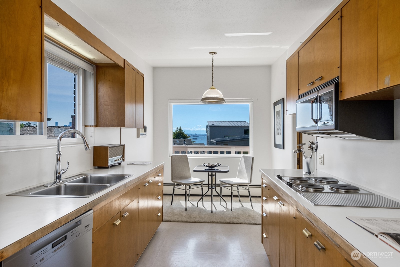 3513 West Howe Street Seattle, WA 98199 - Photo 13 of 39 a kitchen with stainless steel appliances a stove a sink a oven a dining table and chairs