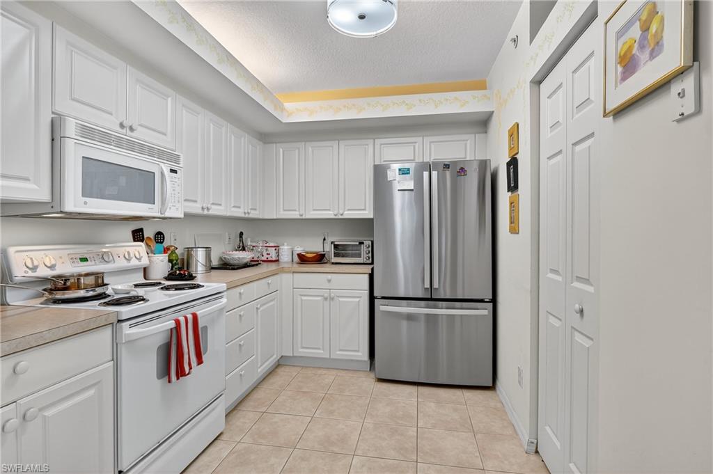 23800 Costa Del Sol Road, Unit 102 Estero, FL 34135 - Photo 11 of 49 a kitchen with stainless steel appliances granite countertop a refrigerator and a stove top oven