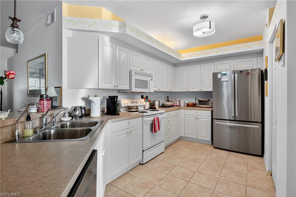 23800 Costa Del Sol Road, Unit 102 Estero, FL 34135 - Photo 12 of 49 a kitchen with a sink appliances and cabinets