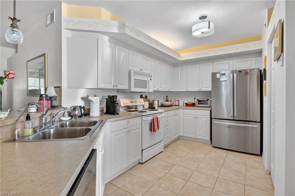 23800 Costa Del Sol Road, Unit 102 Estero, FL 34135 - Photo 13 of 49 a kitchen with a sink appliances and cabinets