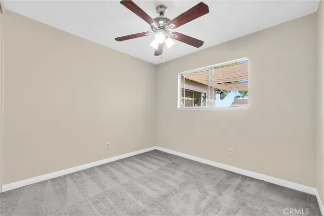 an empty room with a chandelier fan and windows