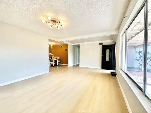 a view of a room with a hanging light and hardwood floor