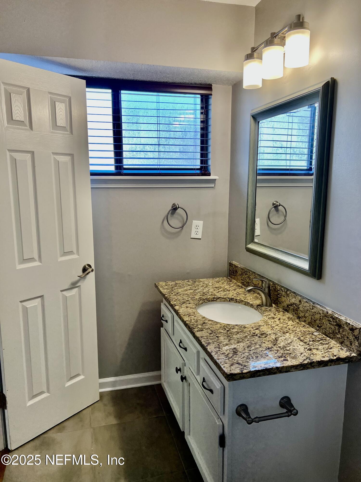 7820 Collins Ridge Boulevard East Jacksonville, FL 32244 - Photo 21 of 27 a bathroom with a granite countertop sink and a mirror