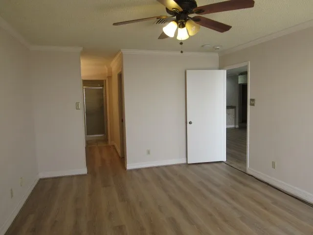 an empty room with wooden floor fan and windows