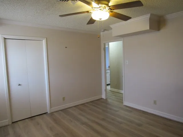 an empty room with wooden floor and fan