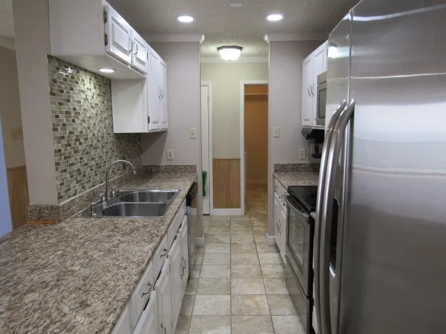 a kitchen with stainless steel appliances granite countertop a sink a stove and a refrigerator