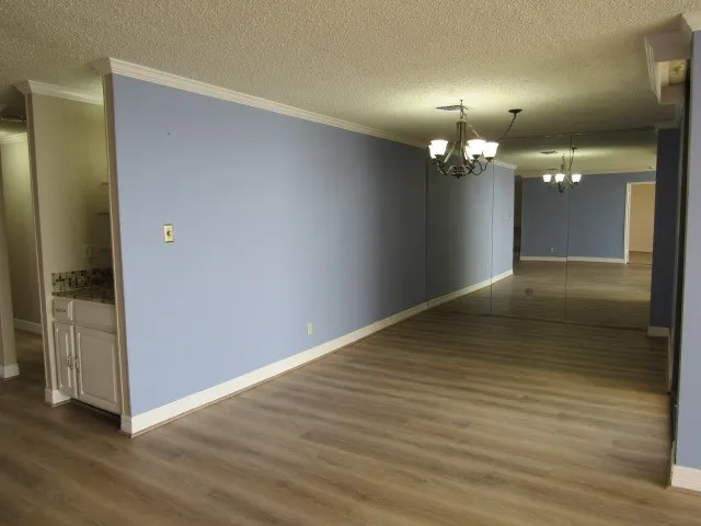 an empty room with wooden floor and chandelier