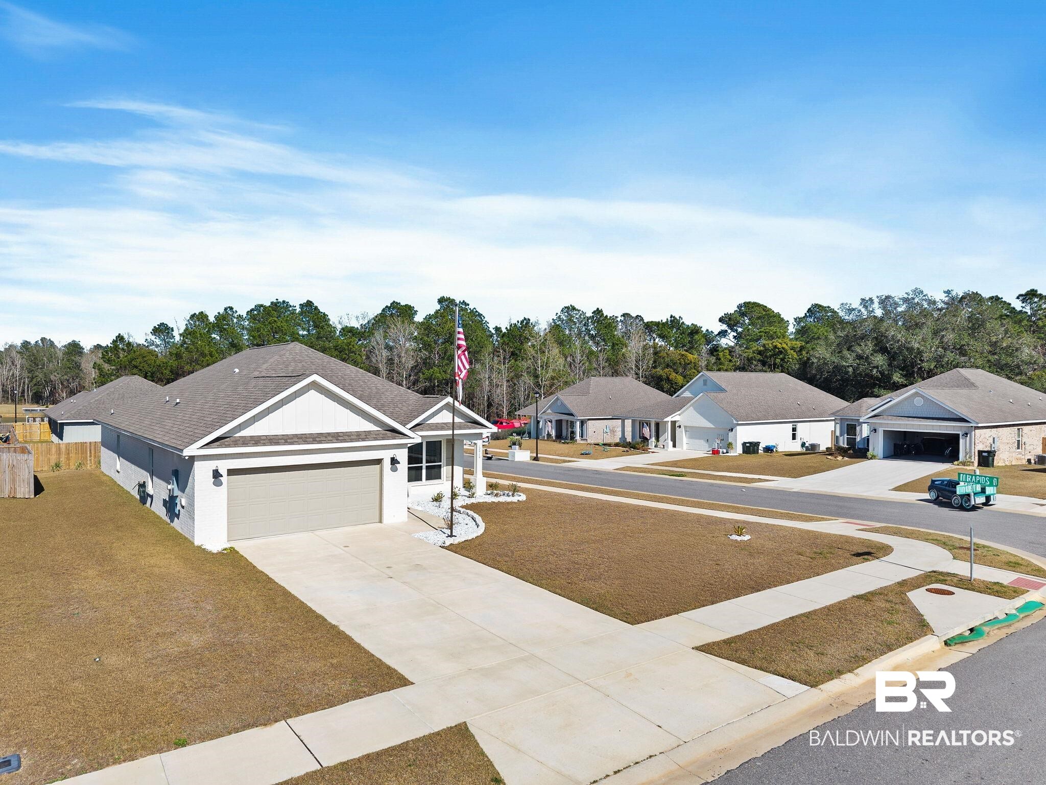 12919 Torrent Road Fairhope, AL 36532 - Photo 57 of 74 View of green lawn with a residential view, driveway, an attached garage, and view of scattered trees