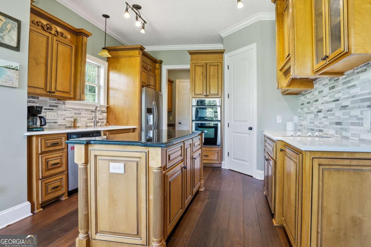 135 Stewart Street St. Simons, GA 31522 - Photo 10 of 27 a kitchen with stainless steel appliances granite countertop a refrigerator a stove and a wooden cabinets