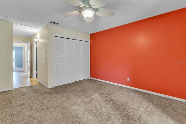 an empty room with closet and a chandelier fan