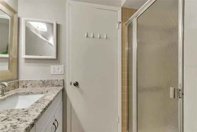 a bathroom with a granite countertop sink and mirror with bathtub