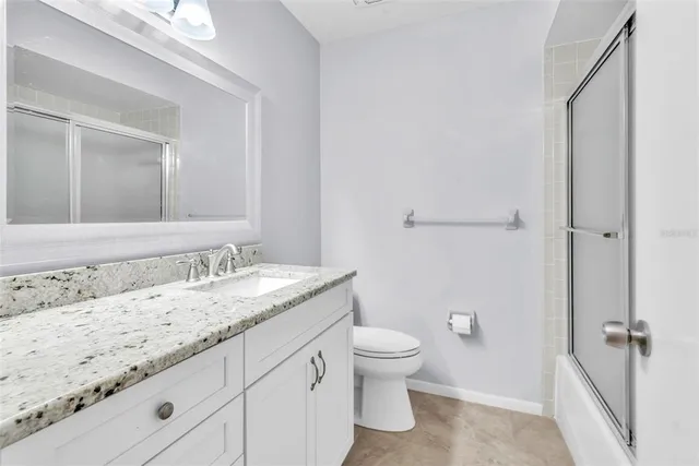 a bathroom with a granite countertop sink a toilet and a mirror