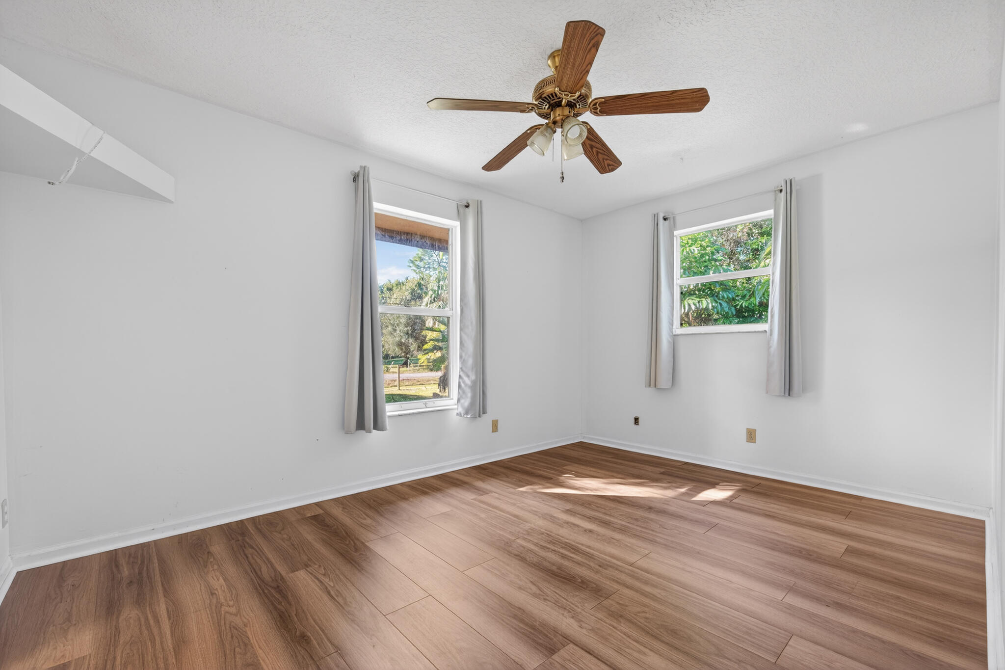 17889 62nd Road North The Acreage, FL 33470 - Photo 11 of 32 a view of empty room with wooden floor and fan