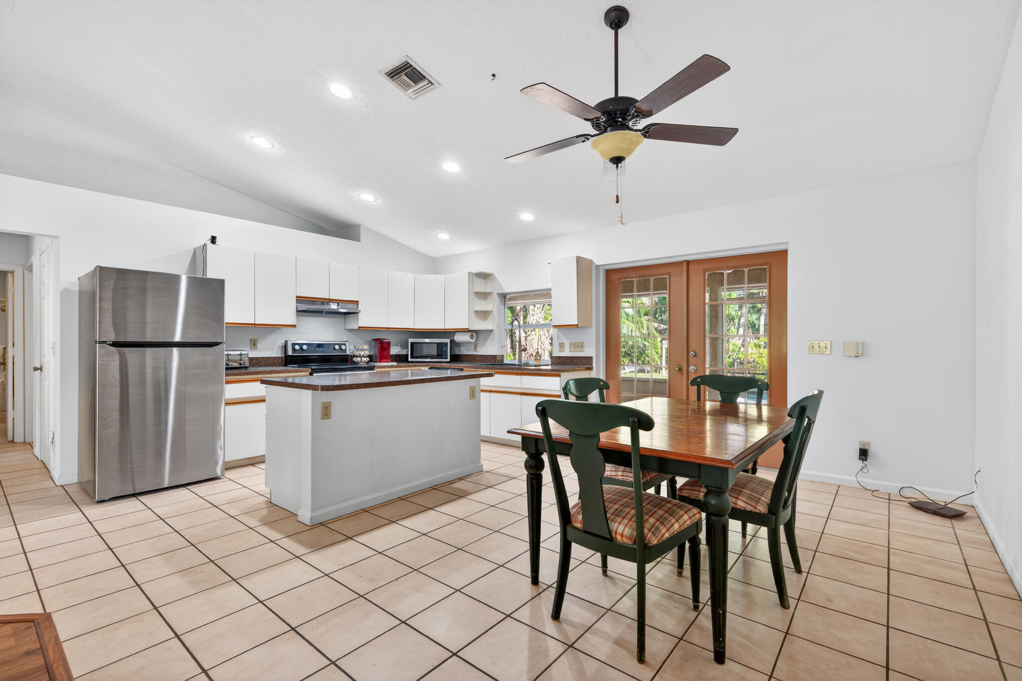 17889 62nd Road North The Acreage, FL 33470 - Photo 9 of 32 a kitchen with stainless steel appliances kitchen island granite countertop a refrigerator a dining table and chairs