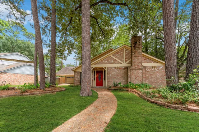a view of a house with a small yard and large trees