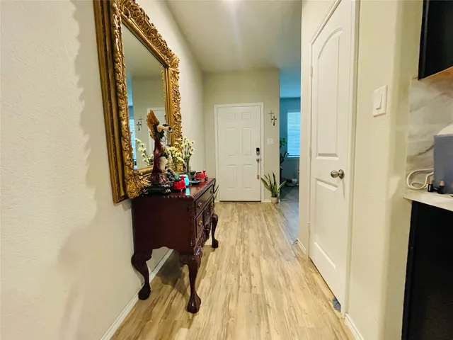 a view of a hallway with wooden floor and a bathroom