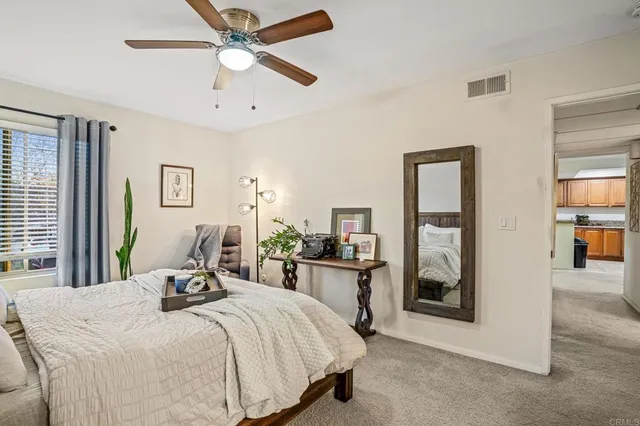 a bedroom with a large bed and a chandelier fan