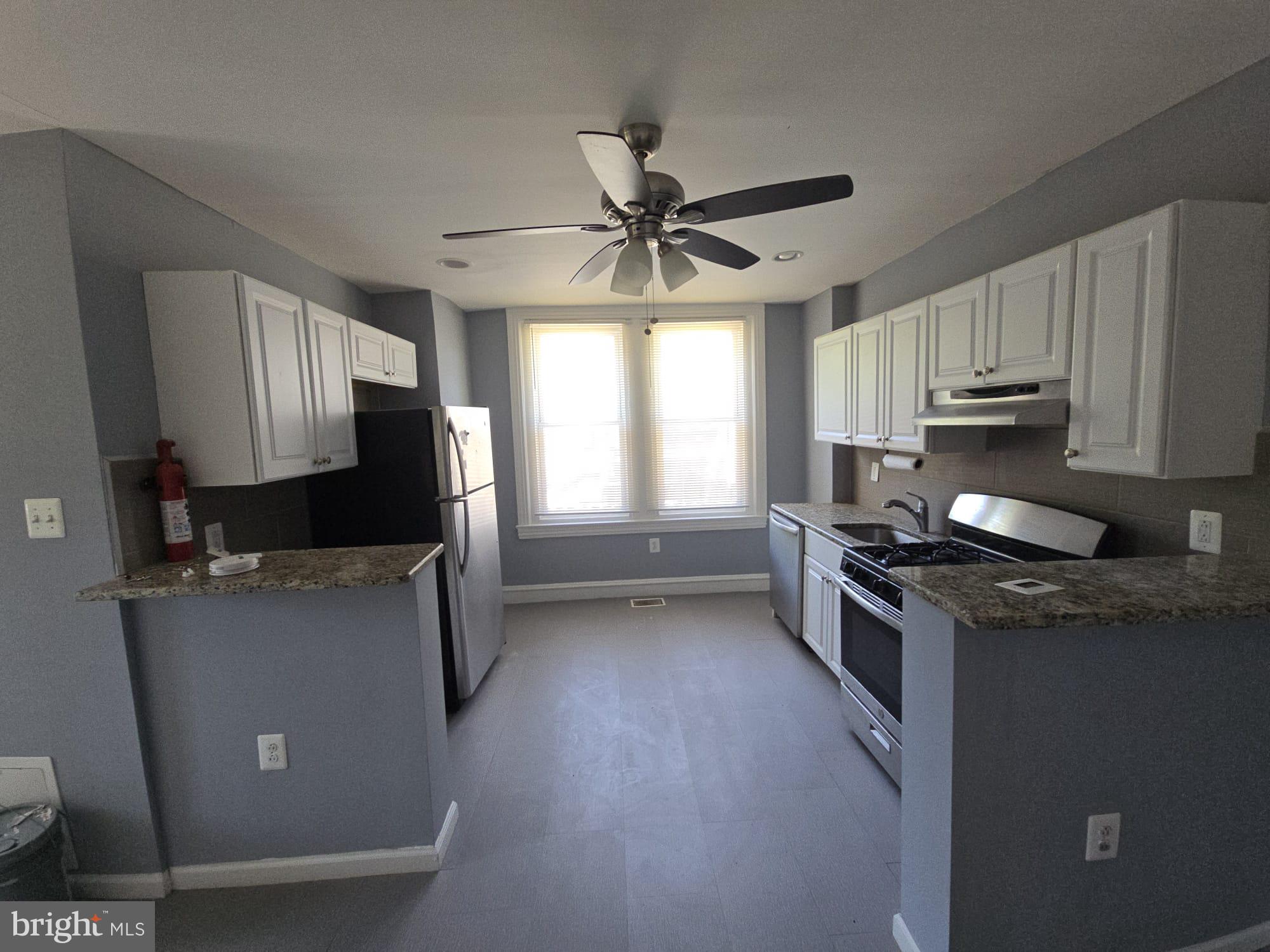 5314 Angora Terrace, Unit 1 Philadelphia, PA 19143 - Photo 8 of 15 a kitchen with granite countertop a stove top oven a sink a window and cabinets