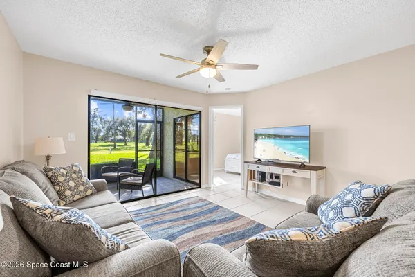 a living room with furniture a flat screen tv and floor to ceiling window