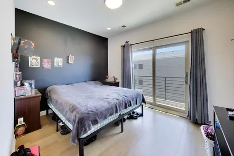 a spacious bedroom with a bed and a flat tv screen on dresser