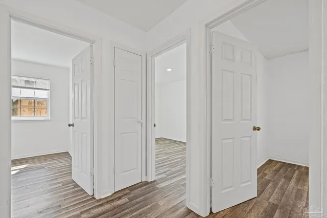 a view of a hallway with wooden floor and closet area