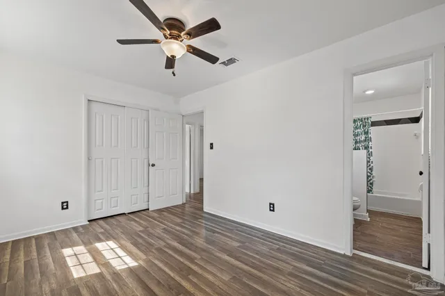 a view of empty room with wooden floor and fan