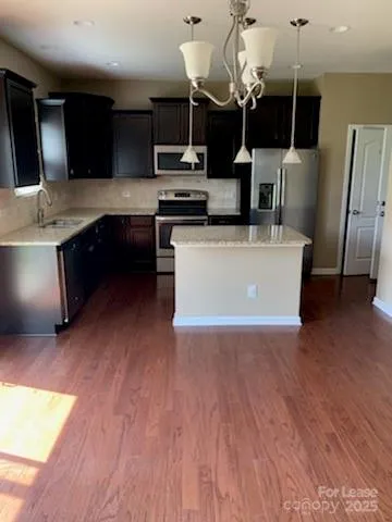 a large kitchen with stainless steel appliances a large counter top a microwave a stove and a wooden floors