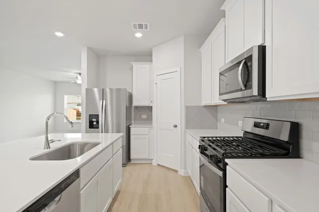 a kitchen with stainless steel appliances granite countertop a sink stove microwave and refrigerator