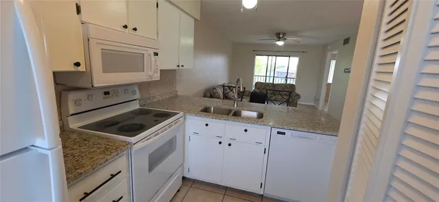 a kitchen with granite countertop white cabinets and white appliances