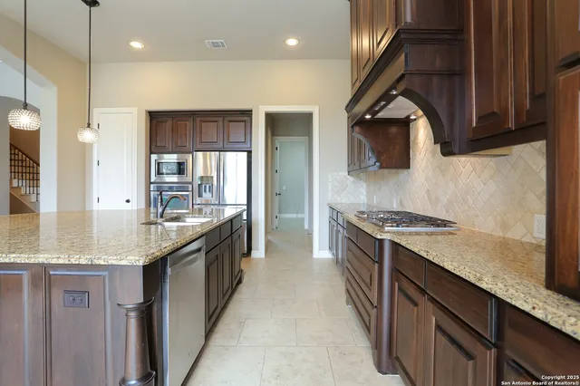 a large kitchen with granite countertop a sink and a stove